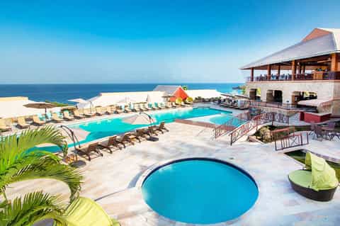 Beachfront resort with multiple pools, lounge chairs, and ocean view beyond