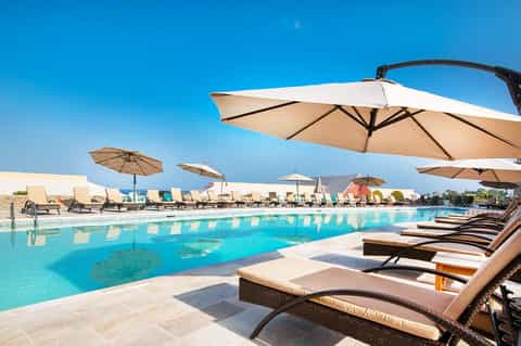 Pool with lounge chairs and large umbrellas providing shade on sunny day