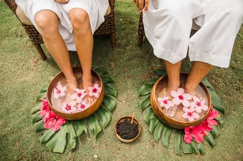 Overhead view of couple's feet in flower petal foot baths during spa treatment