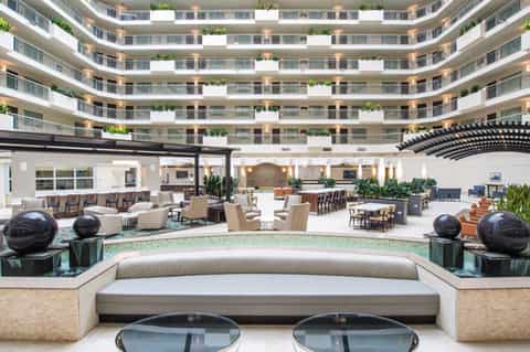 Modern circular hotel atrium lobby with curved balconies, seating areas, and decorative plants