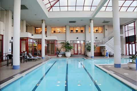 Indoor lap pool facility with skylights, columns, and surrounding lounge seating
