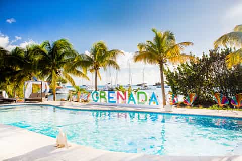 Colorful Grenada sign at pool overlooking Caribbean ocean and sailboats