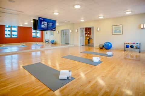Modern fitness studio with yoga mats, exercise balls, and mirror wall for group classes