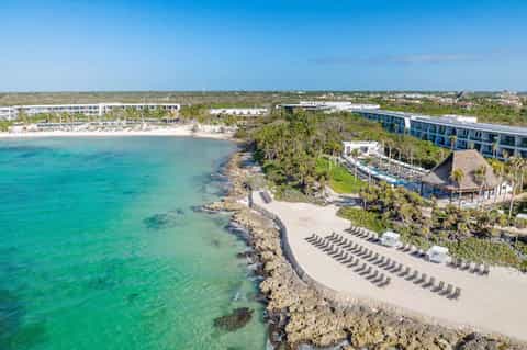 Aerial view of beachfront resort with lounge chairs and rocky coastline