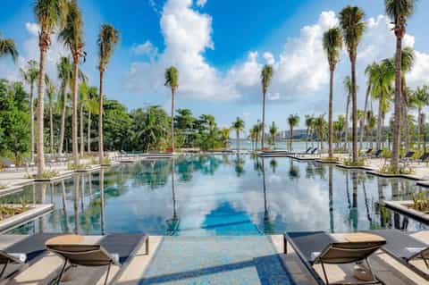 Infinity pool reflecting palm trees and sky with loungers and tropical landscaping