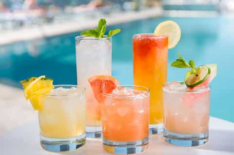 Colorful tropical cocktails with fresh citrus and mint garnish poolside