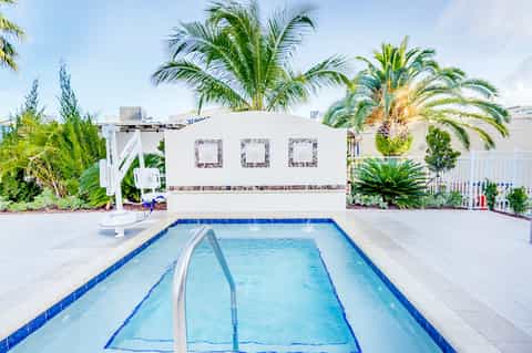 Rectangular swimming pool with palm trees and white cabana structure in tropical resort setting