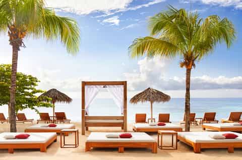 Luxury beach resort with wooden loungers, tiki umbrellas, and ocean view at tropical destination