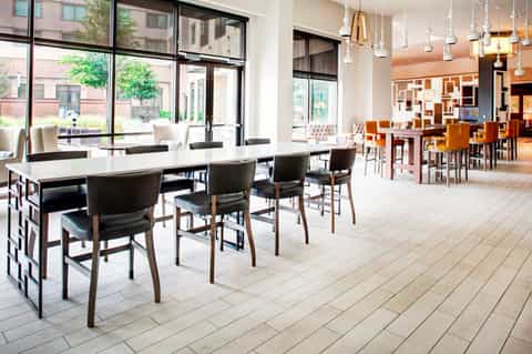 Contemporary hotel dining area with white tables, modern lighting, and floor-to-ceiling windows