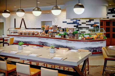 Modern resort dining area with white subway tile, pendant lights, and fresh food display counter