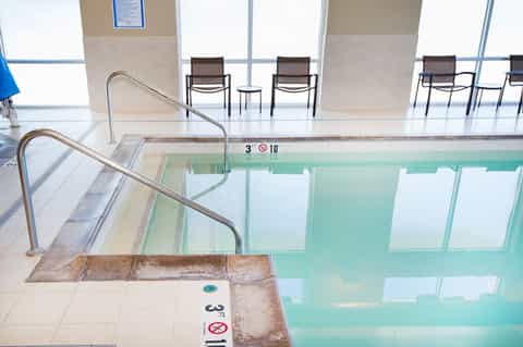 Indoor swimming pool with depth markers and metal railings in a bright, modern facility
