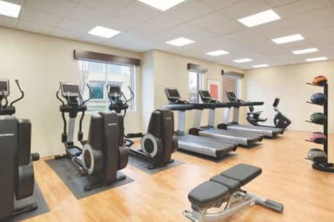 Modern fitness center with elliptical machines, treadmills, and exercise equipment on wooden floor