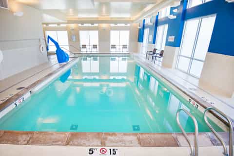 Indoor lap pool with turquoise water, blue walls, and large windows in a bright facility
