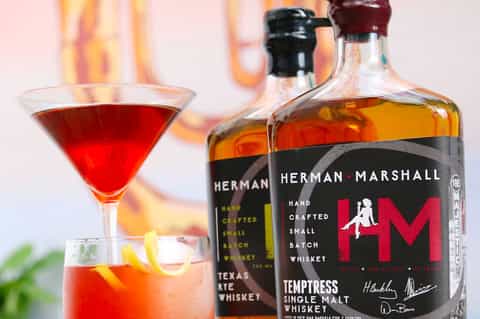 Herman Marshall whiskey bottles and cocktails with fire backdrop for bar promotion