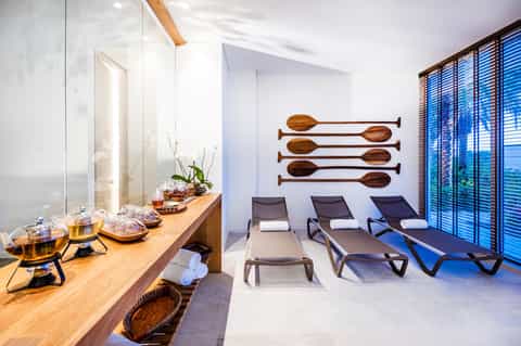 Spa relaxation room with lounge chairs, wooden oar wall art, and ocean view