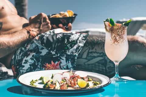 Gourmet ceviche dish with mojito cocktail served poolside overlooking ocean