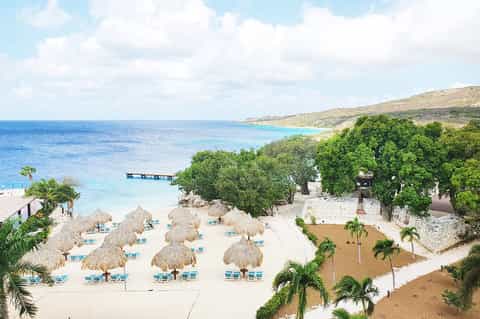 Beachfront resort with thatched umbrellas, white sand, and turquoise water