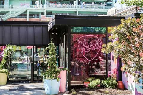 Modern restaurant entrance with neon heart sign and pink and yellow planters