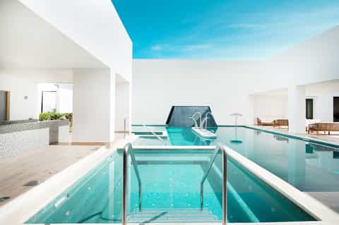 Indoor swimming pool with bright turquoise water and modern white architecture with skylight