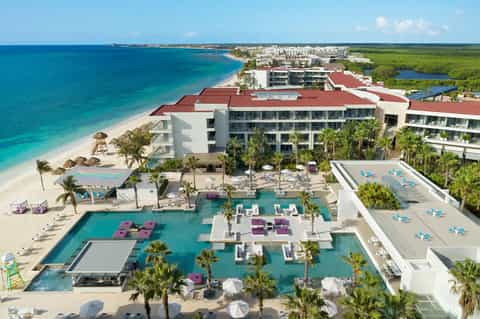 Beachfront resort with multiple pools and palm trees overlooking turquoise ocean