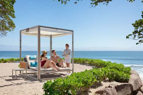 Couple relaxing in modern beach cabana with ocean view and natural vegetation