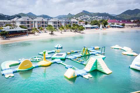 Inflatable water park with various floating obstacles and slides in turquoise shallow water