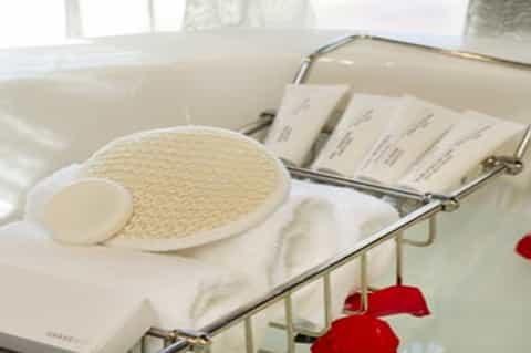 Spa treatment supplies including exfoliating scrub pads and white towels in bathroom setting