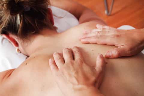 Spa massage therapist performing treatment on client's back