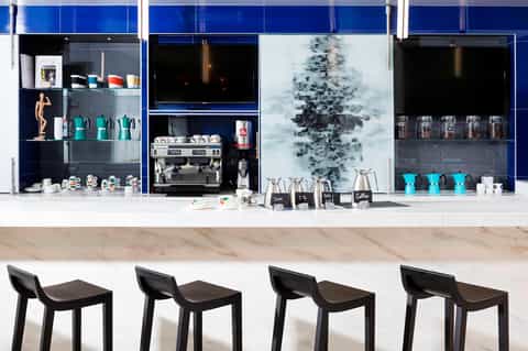 Modern coffee bar with blue cabinetry, espresso machine, and turquoise cups