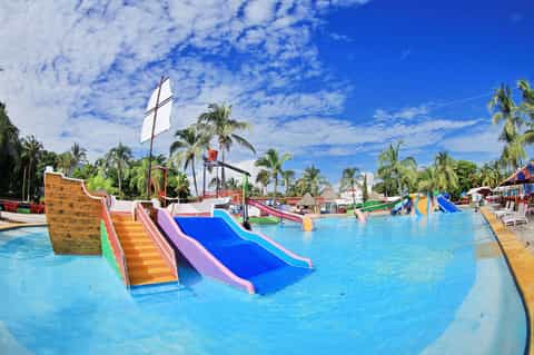 Bright blue water park with colorful slides and sailboat prop under clear blue sky
