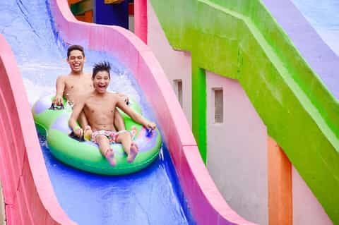 Two people sliding down colorful water slide at resort