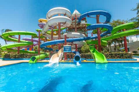 Colorful water slides at resort pool with blue water and clear sky
