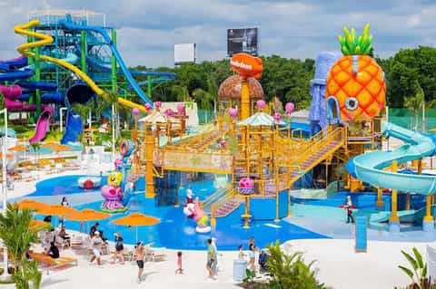 Colorful water park with oversized pineapple structure, water slides, and children's play areas