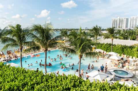 Aerial view of resort pool complex with palm trees and beachfront access