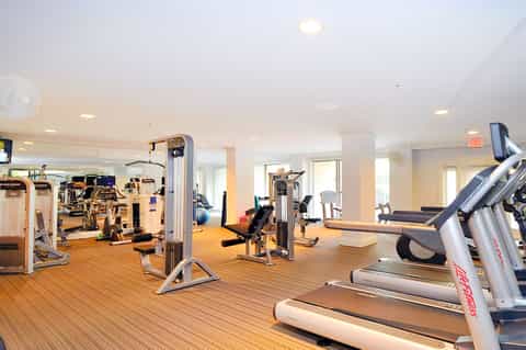 Modern fitness center with cardio equipment, weights, and wooden flooring