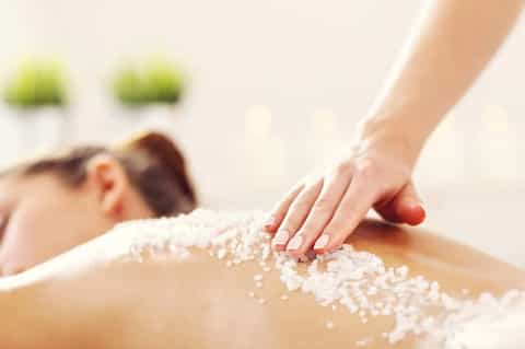 Spa treatment showing salt scrub being applied to client's back