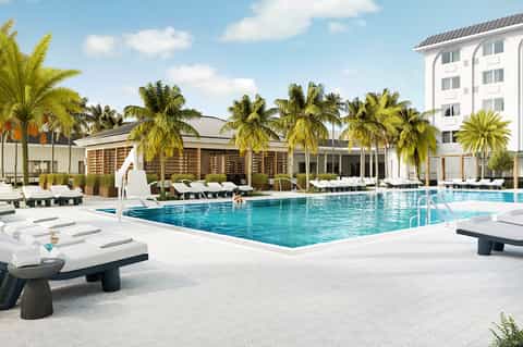 Tropical resort pool with palm trees, white lounge chairs, and modern architecture