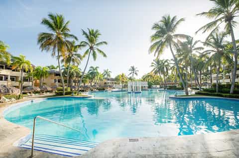 Resort pool with turquoise water, palm trees, and tropical residential buildings