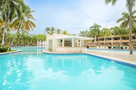 Lagoon-style pool resort with swim-up bar, palm trees, and tropical landscape