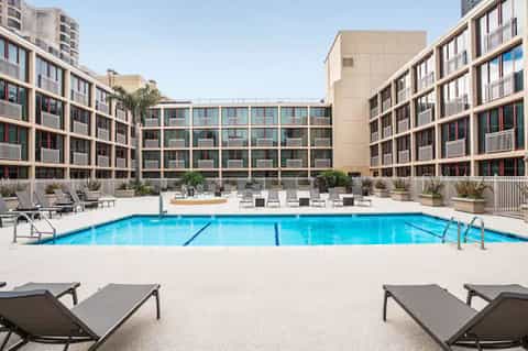 Modern resort courtyard with rectangular swimming pool, lounge chairs, and residential buildings