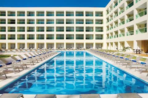 Resort courtyard with Olympic-length pool surrounded by white building and lounge chairs