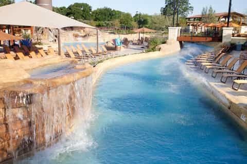 Resort pool with terraced waterfall feature, loungers, and desert landscape views