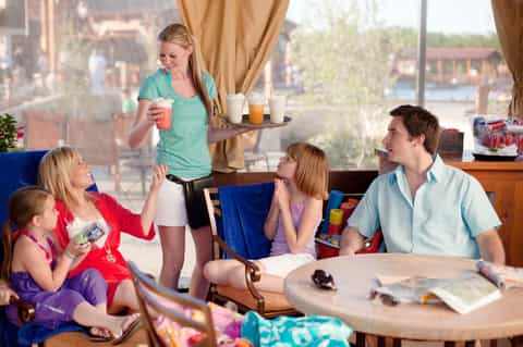 Family enjoying beverages in a high-rise hotel room with city views and gold curtains