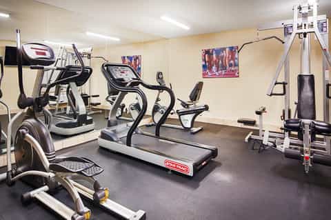 Fitness center with treadmills, stationary bikes, exercise equipment, and motivational posters on walls