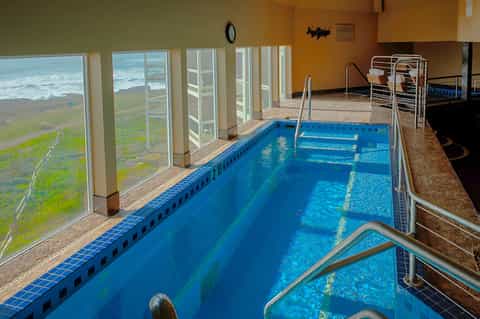 Indoor lap pool with ocean and coastal views through large windows