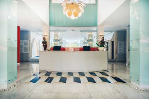 Modern resort reception desk with curved counter, colorful tile accents, and geometric floor pattern