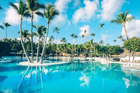 Tropical resort pool with palm trees reflected in crystal-clear turquoise water