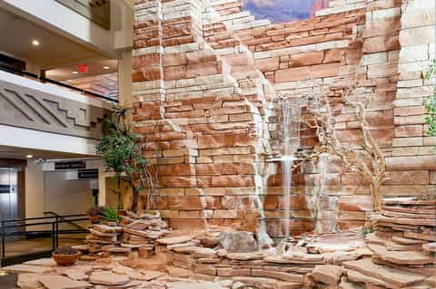 Indoor atrium with massive red stone wall, waterfall feature, and modern architecture