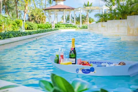 Luxurious pool with floating champagne bar and gazebo, surrounded by lush tropical landscaping