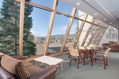 Modern lounge with floor-to-ceiling windows framing mountain and valley views with comfortable seating